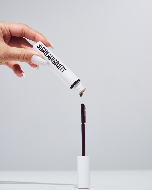 Model holding a tube of brown lash and brow Glaze for lash extensions