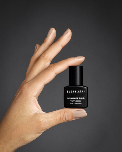 A model holding a bottle of lash extension glue.