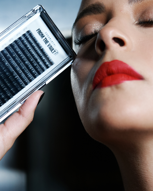 A model holding a tray of From The Vault Soho Silk Lashes near her cheek.