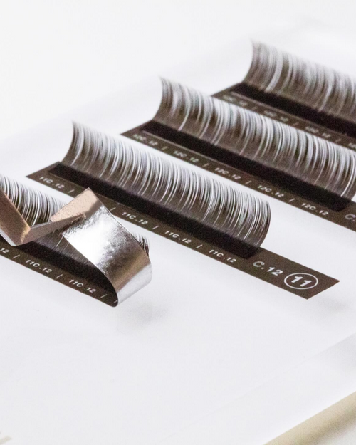 Tweezers pulling up a strip of Brunette lashes.