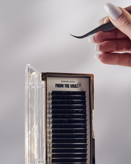 A model holding tweezers above a tray of From The Vault Soho Silk Lashes.