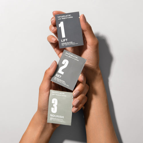 Model holding Lift, Set, and Nourish Lash and Eyebrow Lamination sachets.