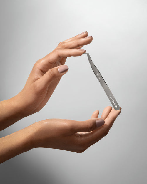 A model holding Volume eyelash extensions Tweezer V-65 between two hands.