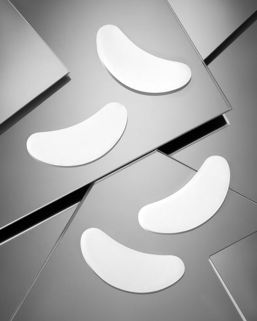 Two pairs of Hydrogel Eye Pads for lash extensions on a gray geometric background.