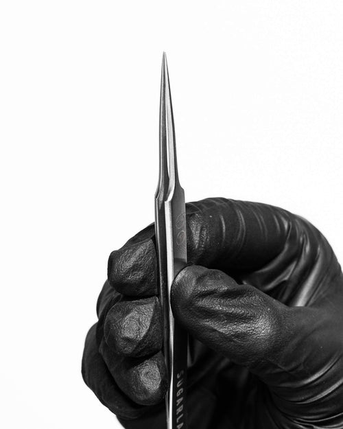 A model's gloved hand holding an I-P isolation Tweezer for eyelash extensions.