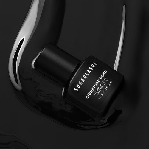 A bottle of lash extension glue with the adhesive around the bottle.