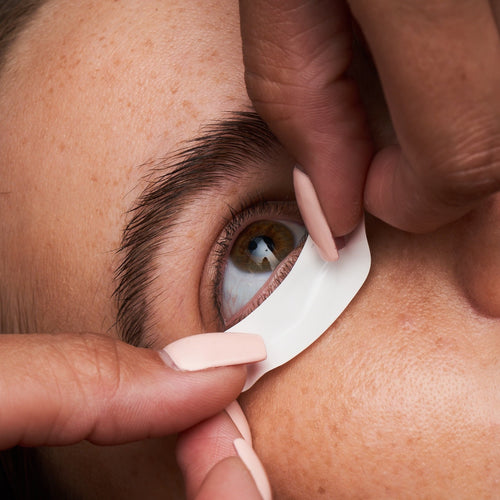 A lash artist applying a Gel Free Eye Pad to a client's under eye for eyelash extensions.