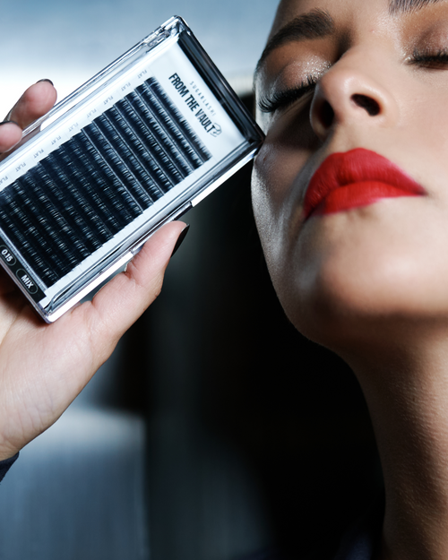 A model holding a tray of From the Vault lashes near her cheek.