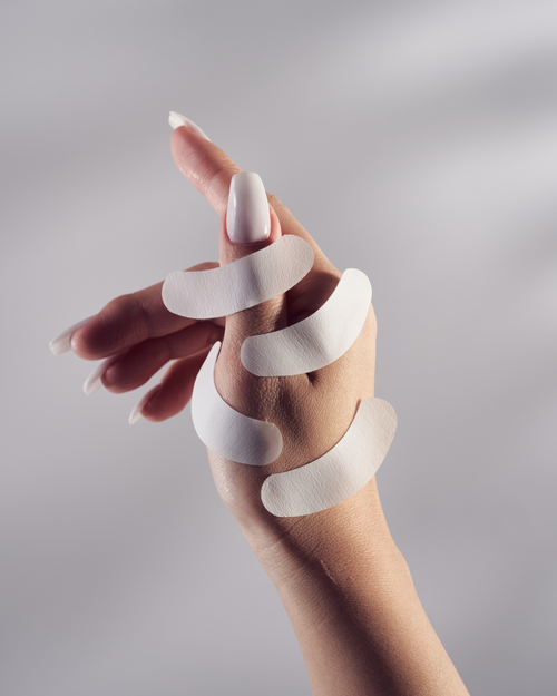 A model's hand with multiple Gel Free Eye Pads stuck to her hand.