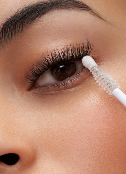 A model's eye with the Cat Eye temporary lashes and a lash brush touching her lashes.