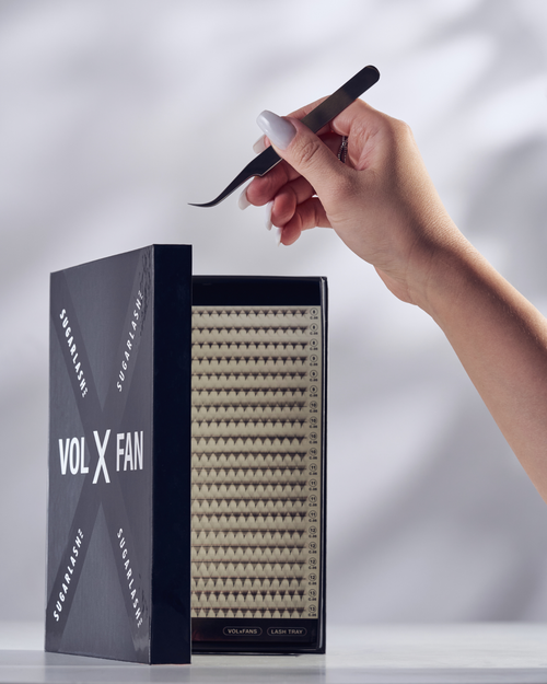 A model holding tweezers above a partially open tray of VOL-X pre-made fans.