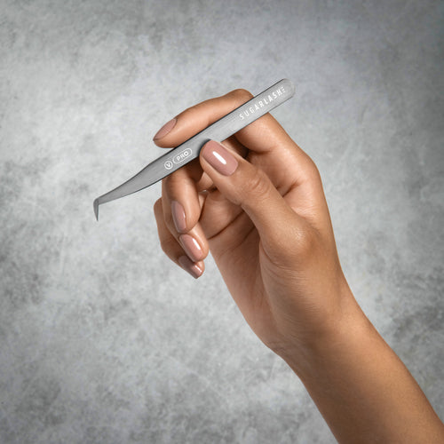 A model holding Volume lash extension Tweezer V-PRO in their hand.