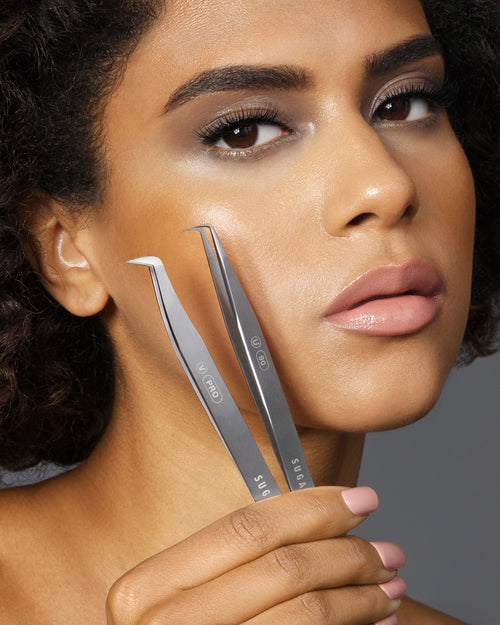 A model holding two Tweezers up near her cheek.